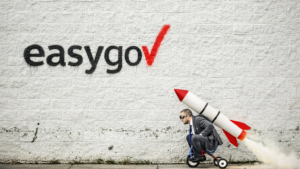 easygov auf eine Mauer gesprayt, davor ein Mann auf einem Dreirad mit einer Rakete auf dem Rücken